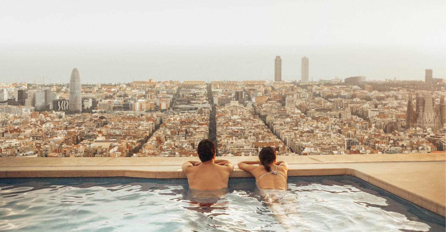 Hotel infinity pool with two people looking at the view of the city